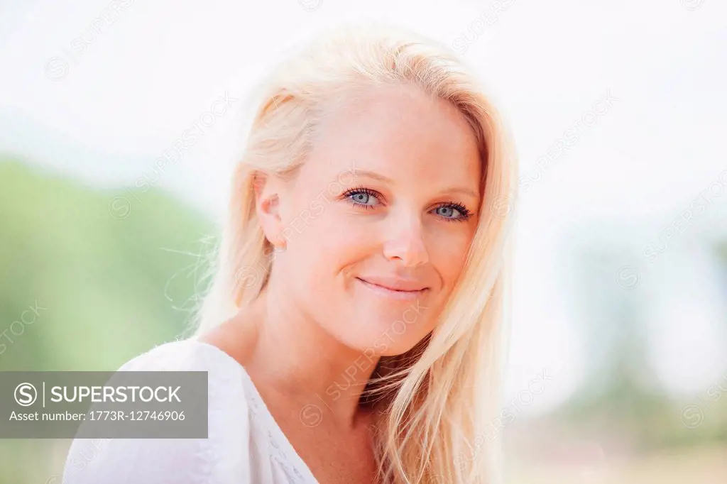 Portrait of long haired young blonde woman looking at camera smiling