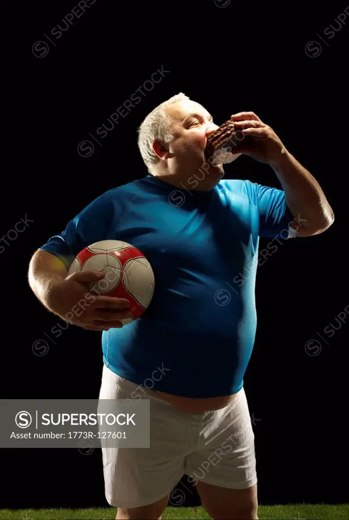 Large footballer holding ball and eating