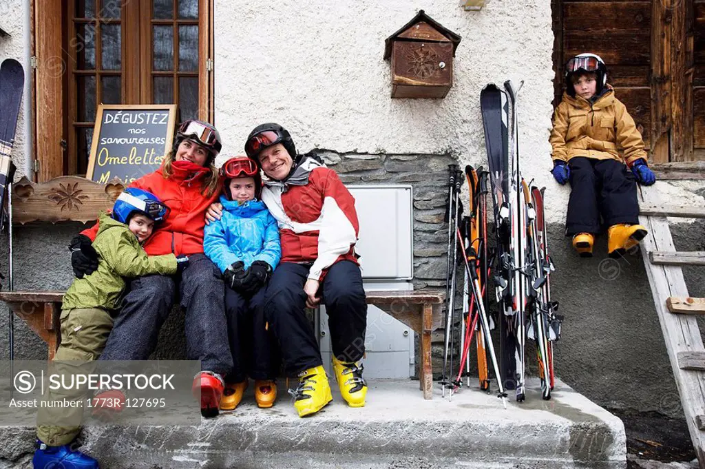 Family sitting outside barn with skis