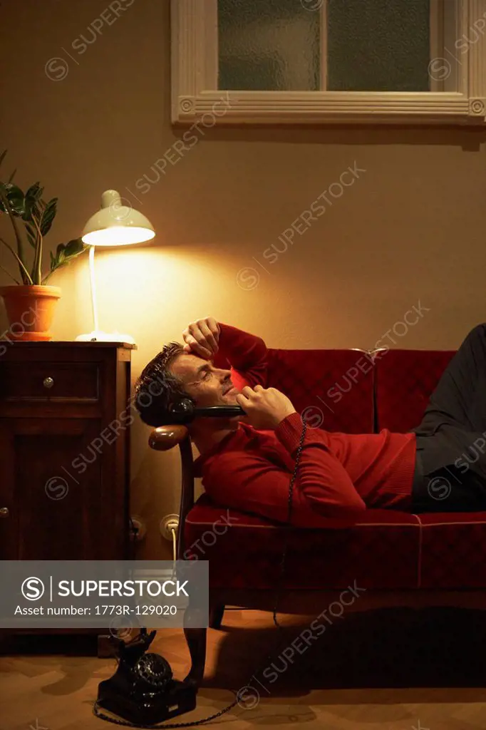 Man lying on couch phoning
