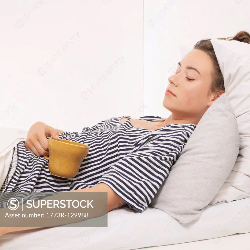 Woman in bed holding a mug