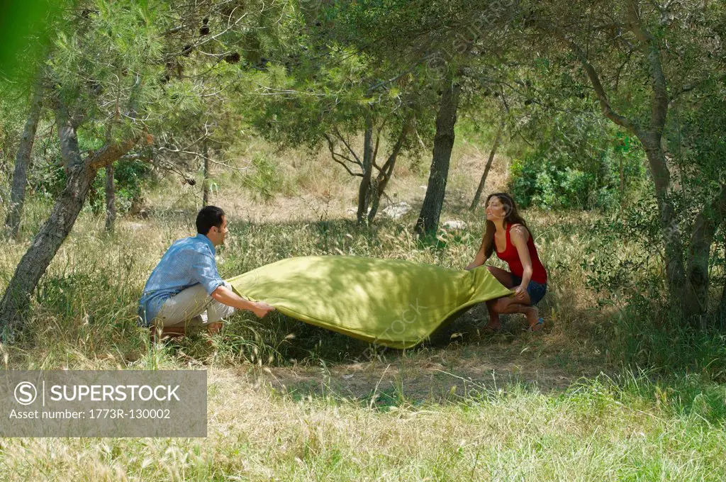 Smiling couple laying out picnic blanket