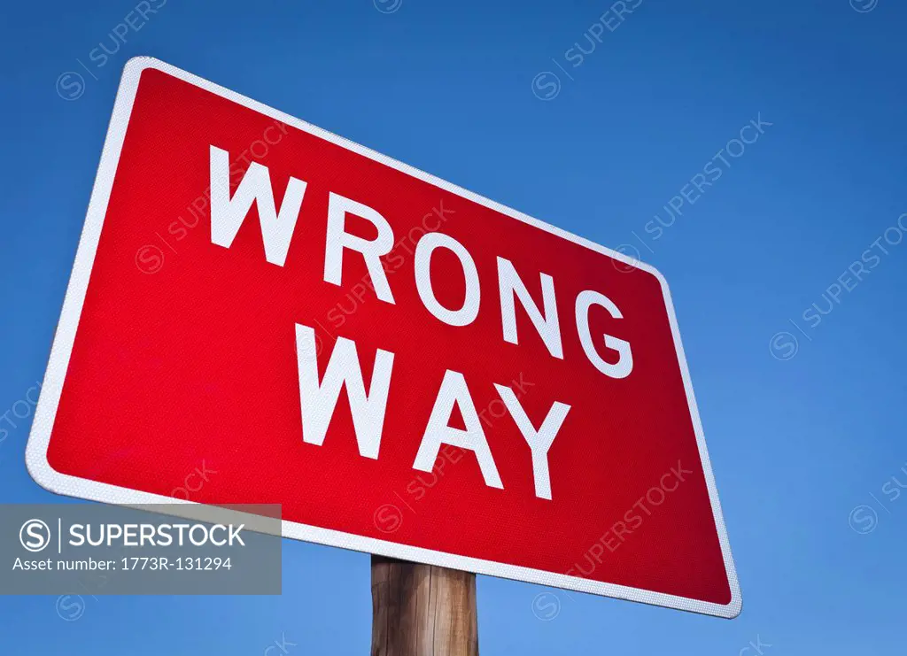 Wrong way sign against blue sky