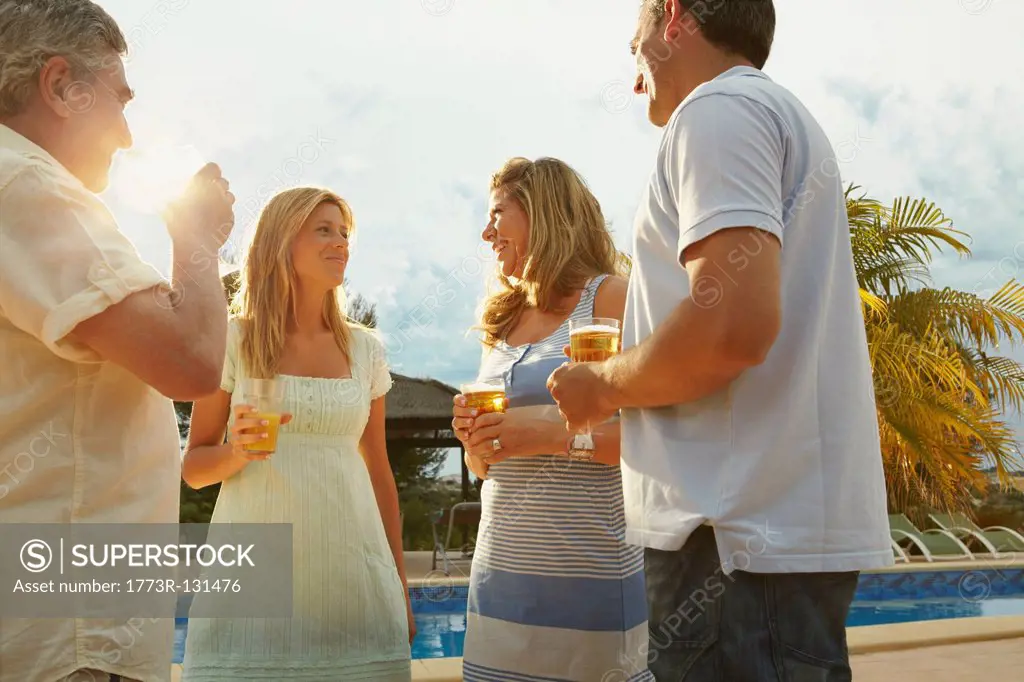 Group of friends having drinks by pool