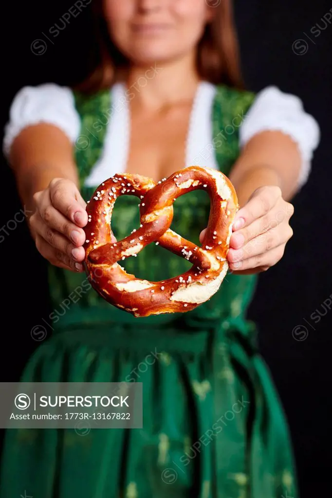 Young woman in Dirndl holding pretzel