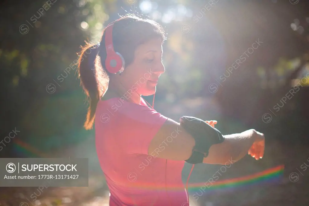 Side view of mature woman wearing headphones preparing armband