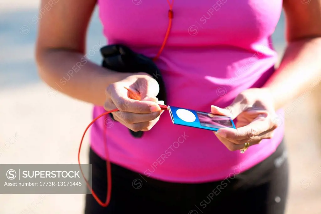 Cropped mid section of mature woman plugging audio jack into mp3 player