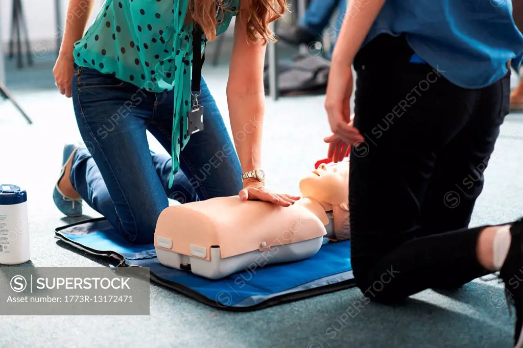 College student performing CPR on mannequin in class