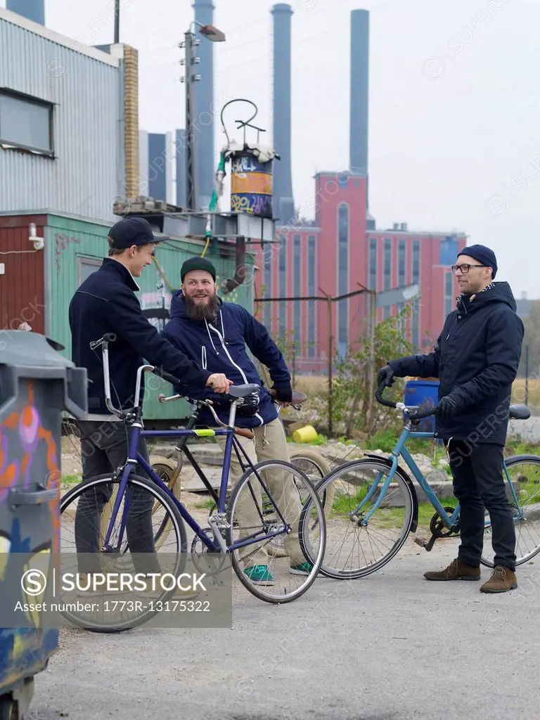Urban cyclists chatting near factory