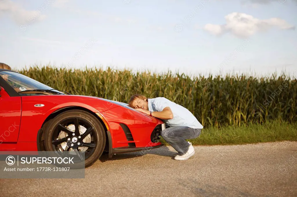 Man hugging his electric sports car