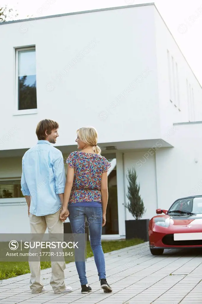 Couple in front of house + electric car