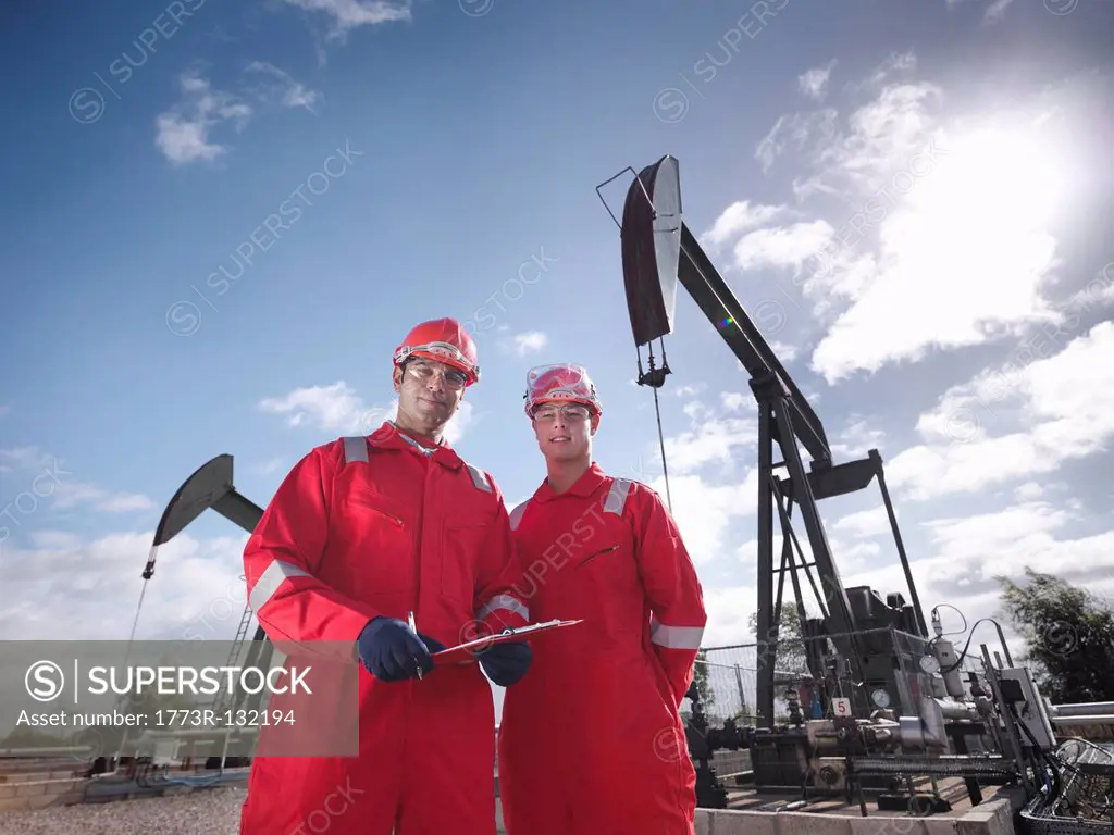 Two workers in front of oil wells