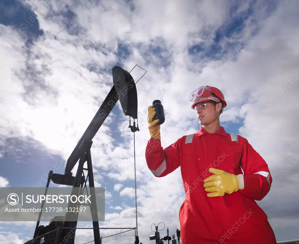 Worker inspecting crude oil at oil well