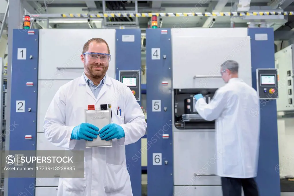 Scientist with lithium ion pouch cell manufacture machine in battery research facility, portrait
