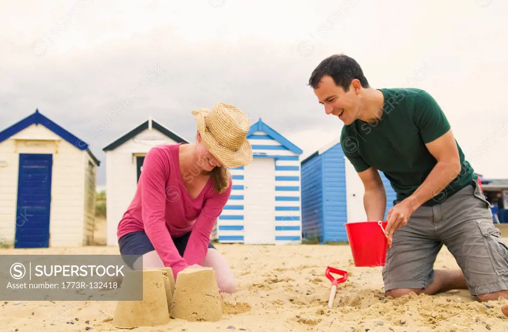 Happy couple make sandcastles on beach
