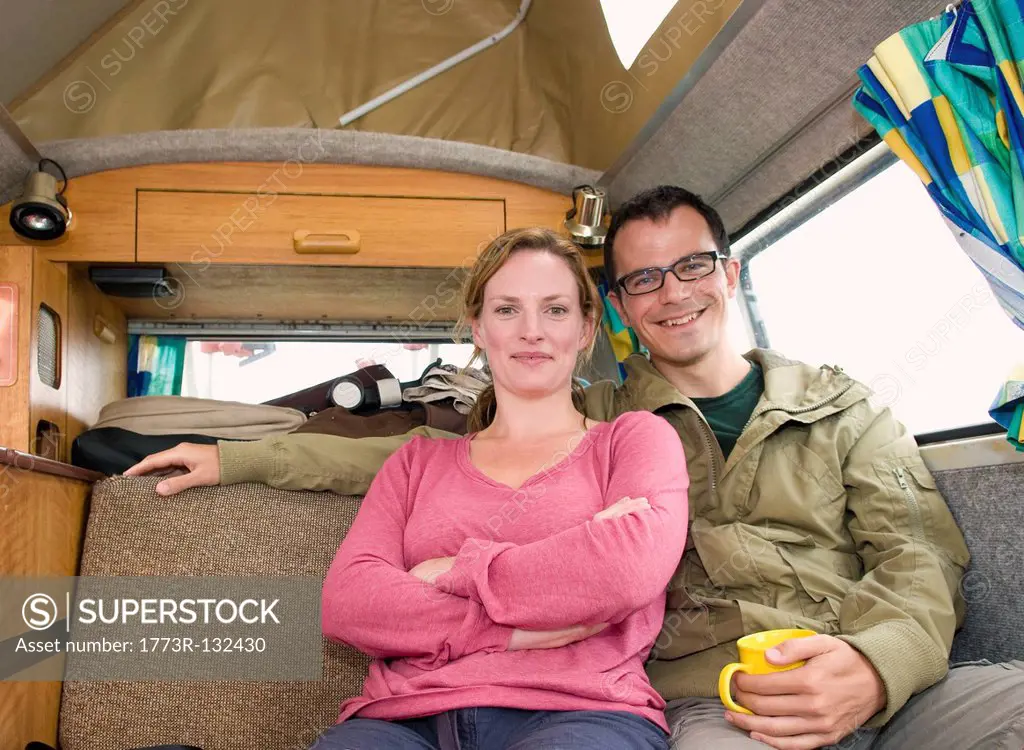 Happy couple sit in camper van