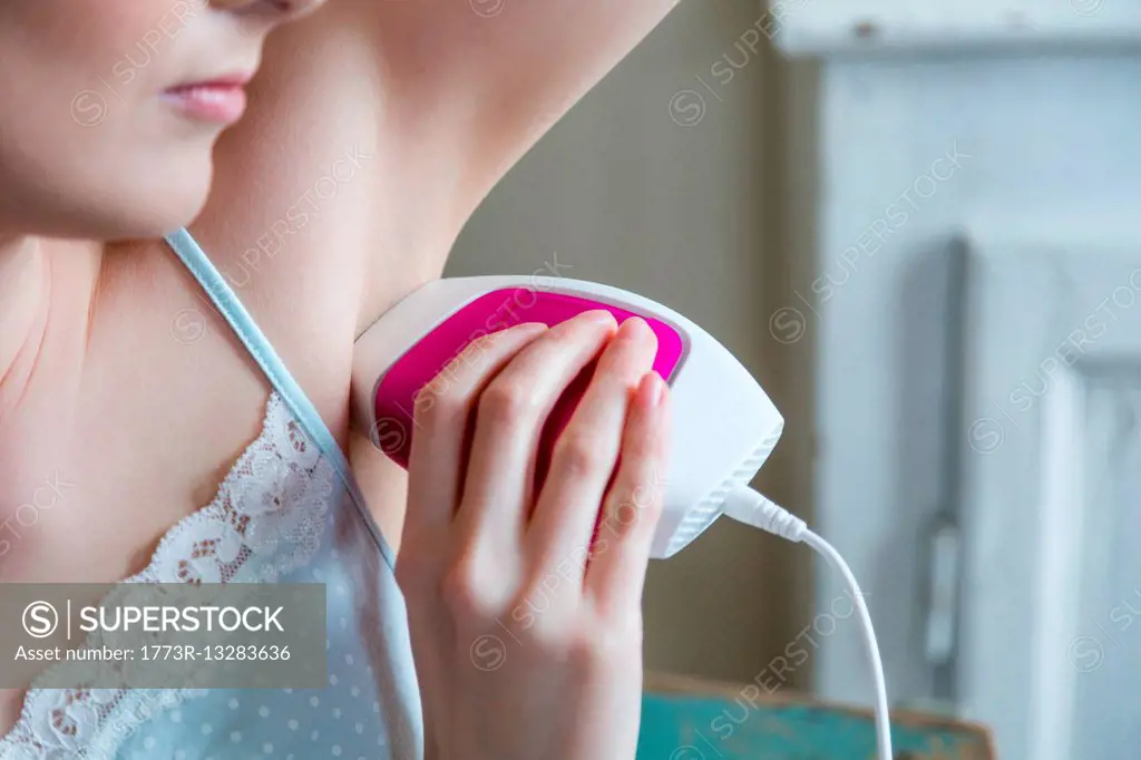 Cropped view of woman using electric shaver to shave armpit