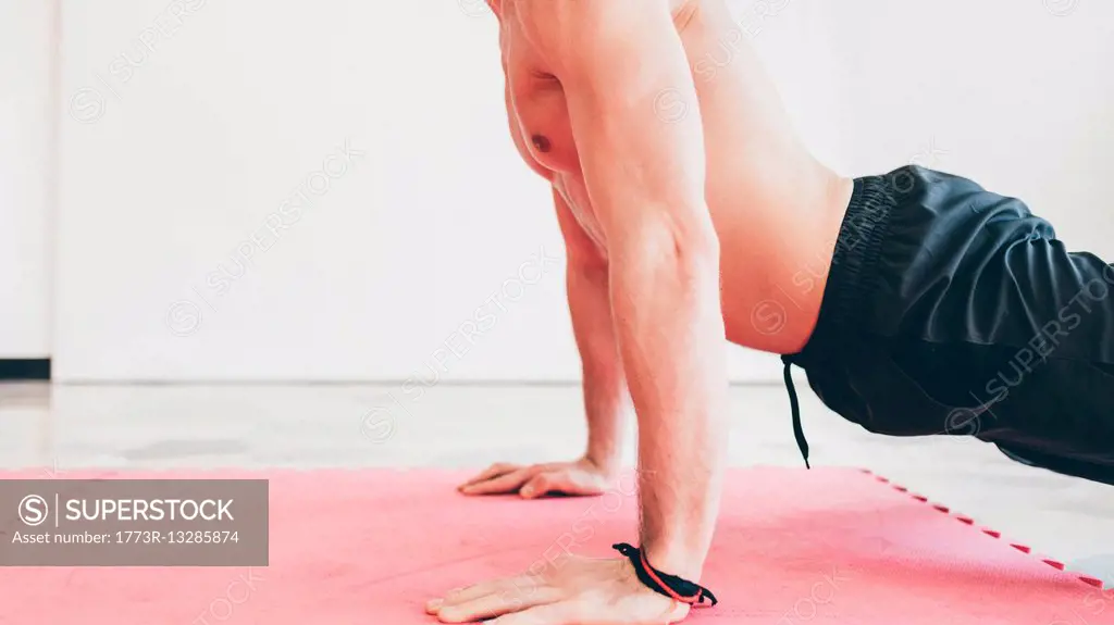 Side view of man in gym doing push ups