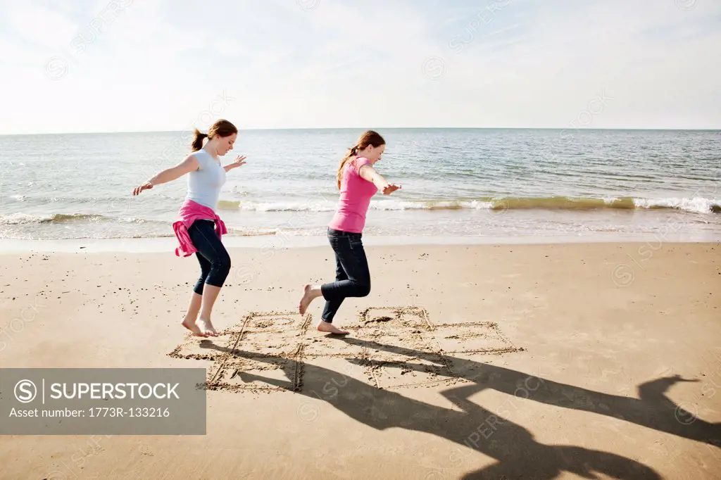 Girls playing hopscotch on beach