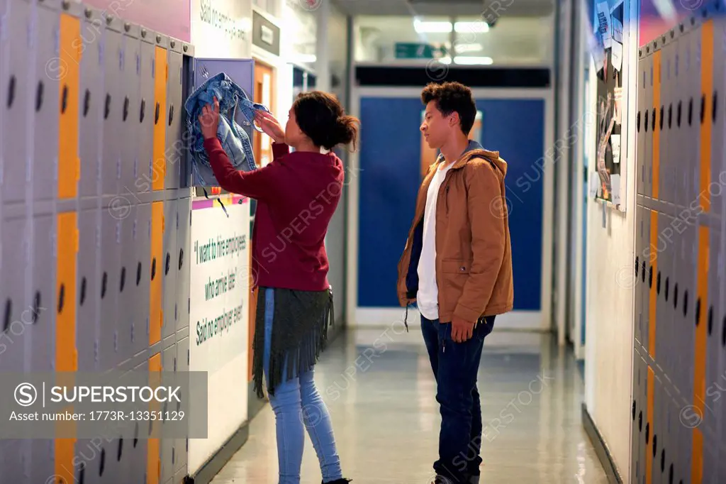 Young female student removing jacket from college locker