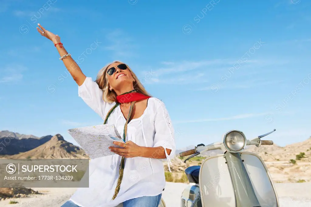 Woman sitting on motorbike with map