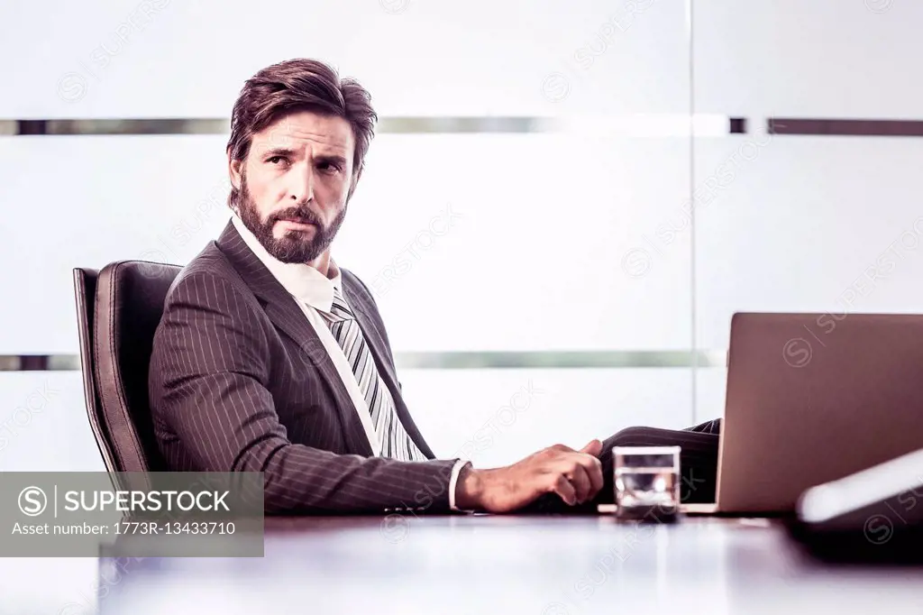 Confident businessman looking over shoulder from office desk