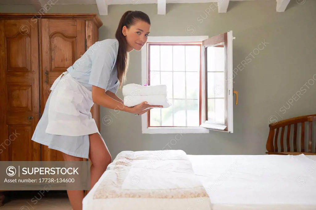 Hotel maid in room with pile of towels