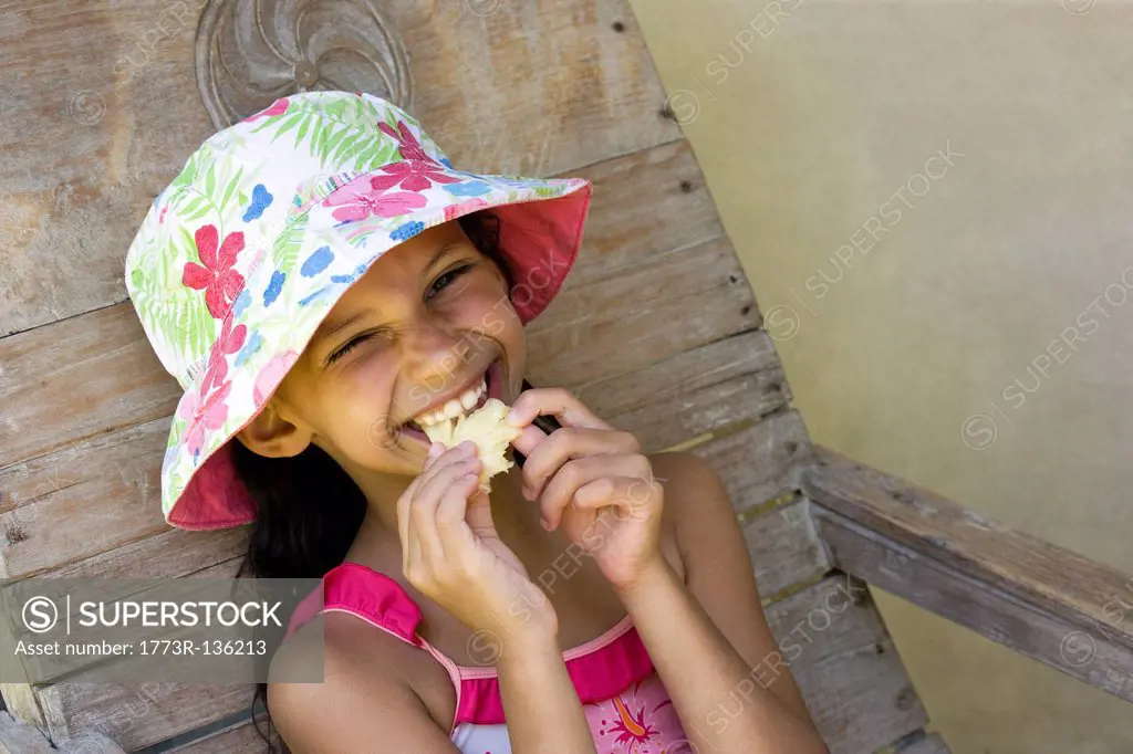 Youg girl with a hat eating pineapple
