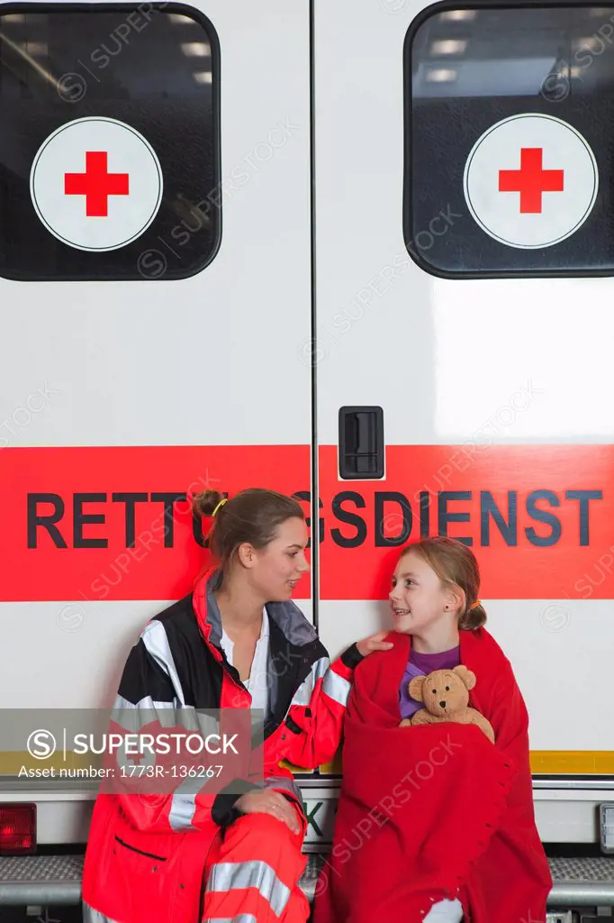 Ambulance woman calming girl at coach