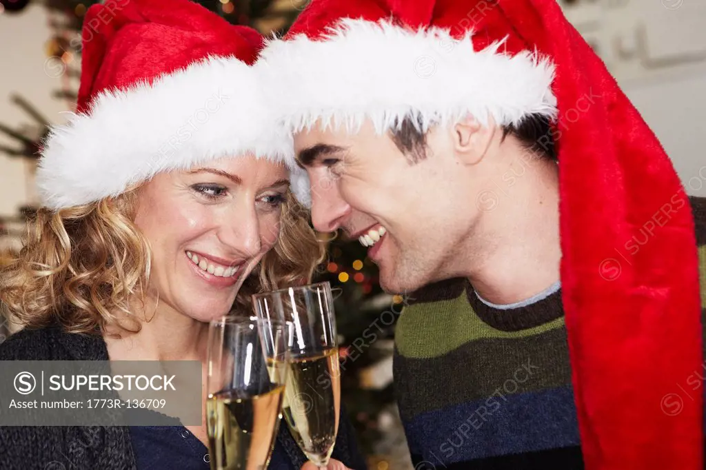 Couple with xmas caps clinking glasses