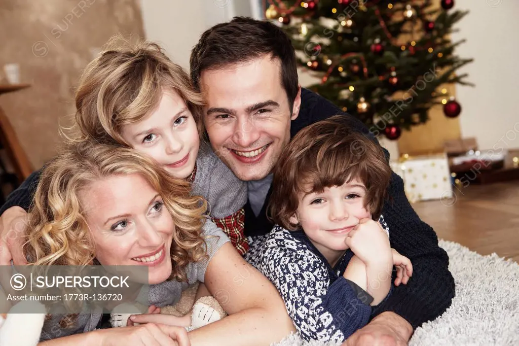 Family lying on carpet in front of tree