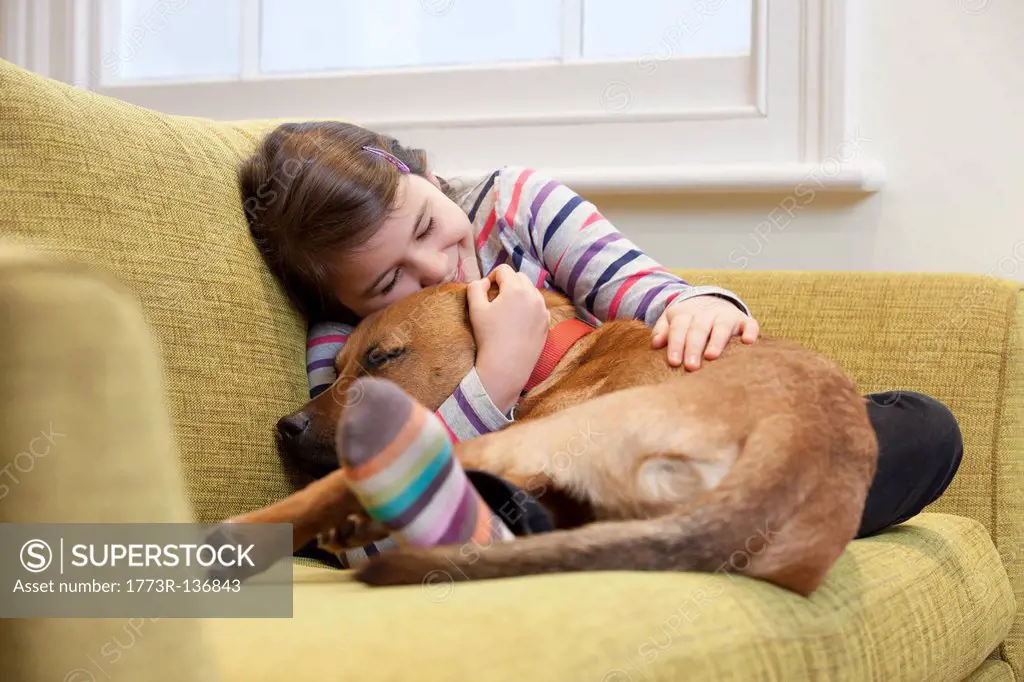 Young girl cuddling her dog on the sofa