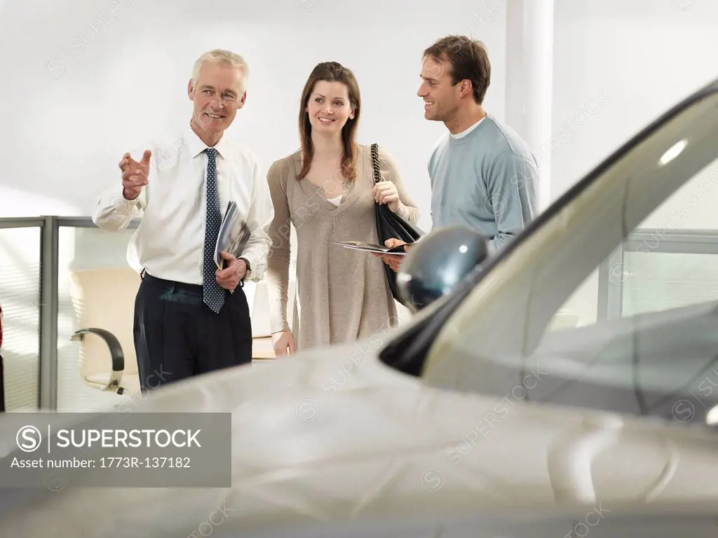 Salesman and customers in car dealership