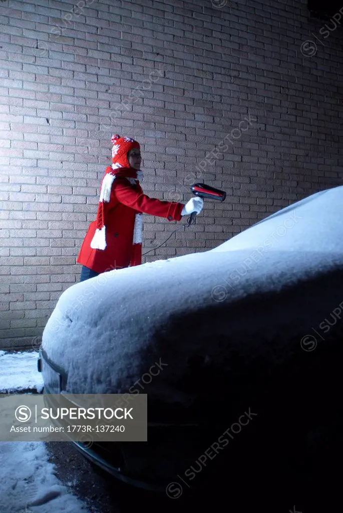 Girl defrosting car with hair drier