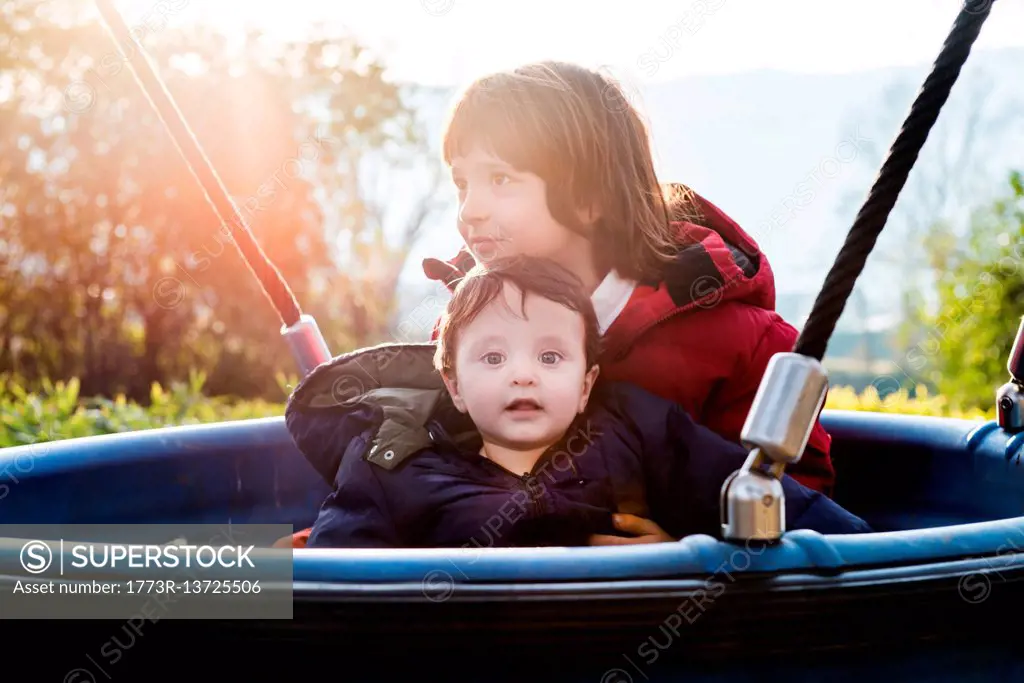 Portrait of baby boy with brother on playground ride in park