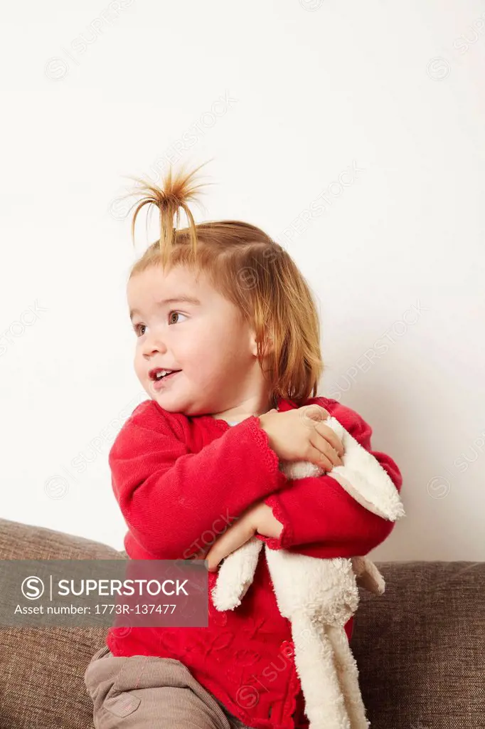 Young girl with teddy bear on sofa