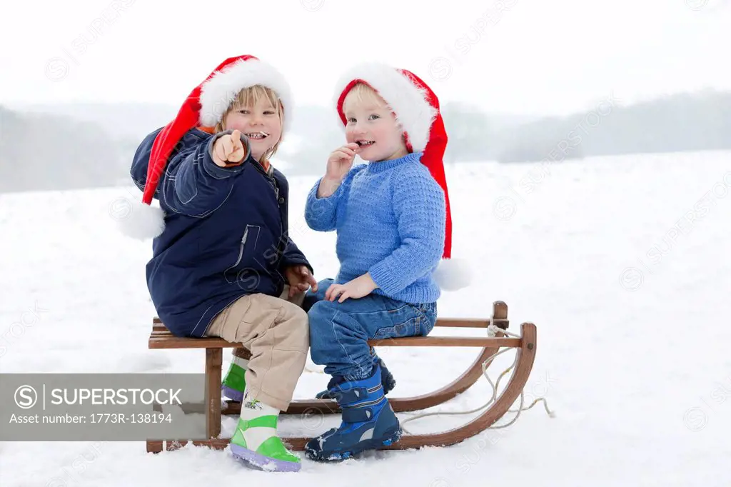 Two boys on a sledge wearing Xmas hats