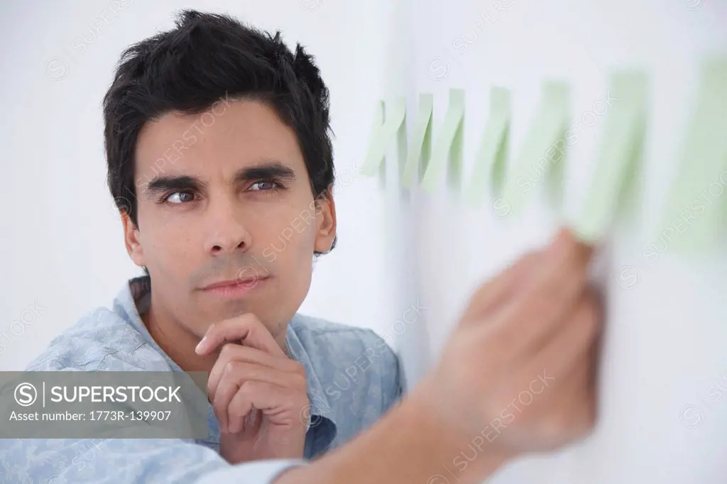 Man arranging post_it notes and thinking