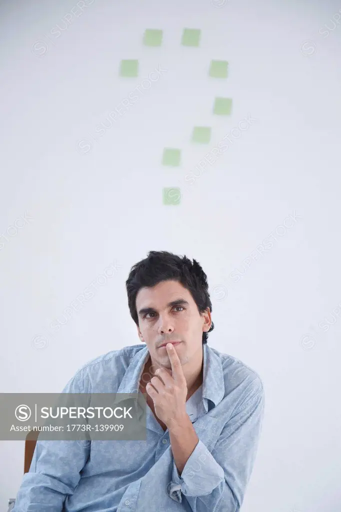 Man thinking with post_it note question makr behind him