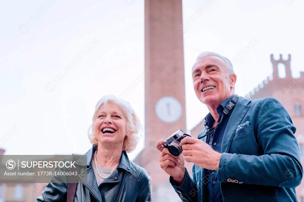 Tourist couple with digital camera in town square, Siena, Tuscany, Italy