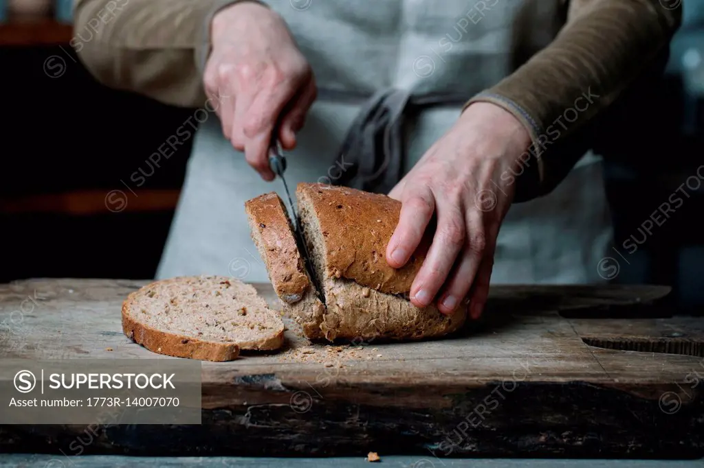 Woman slicing bread on chopping board, mid section