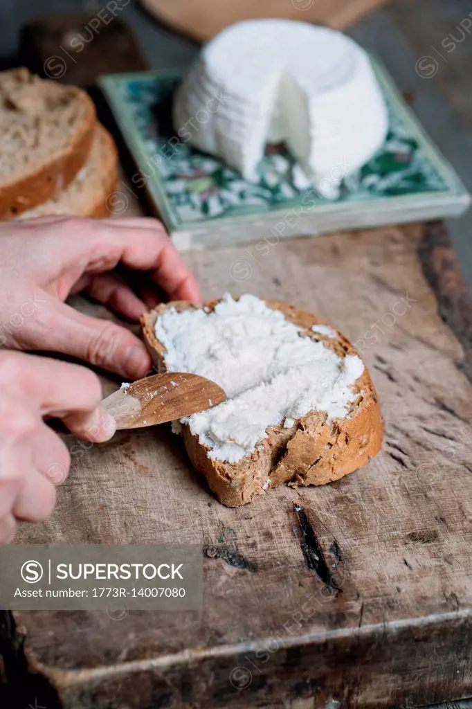 Woman spreading ricotta cheese onto slice of bread, close-up