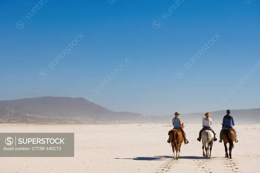 3 people riding horses on the beach