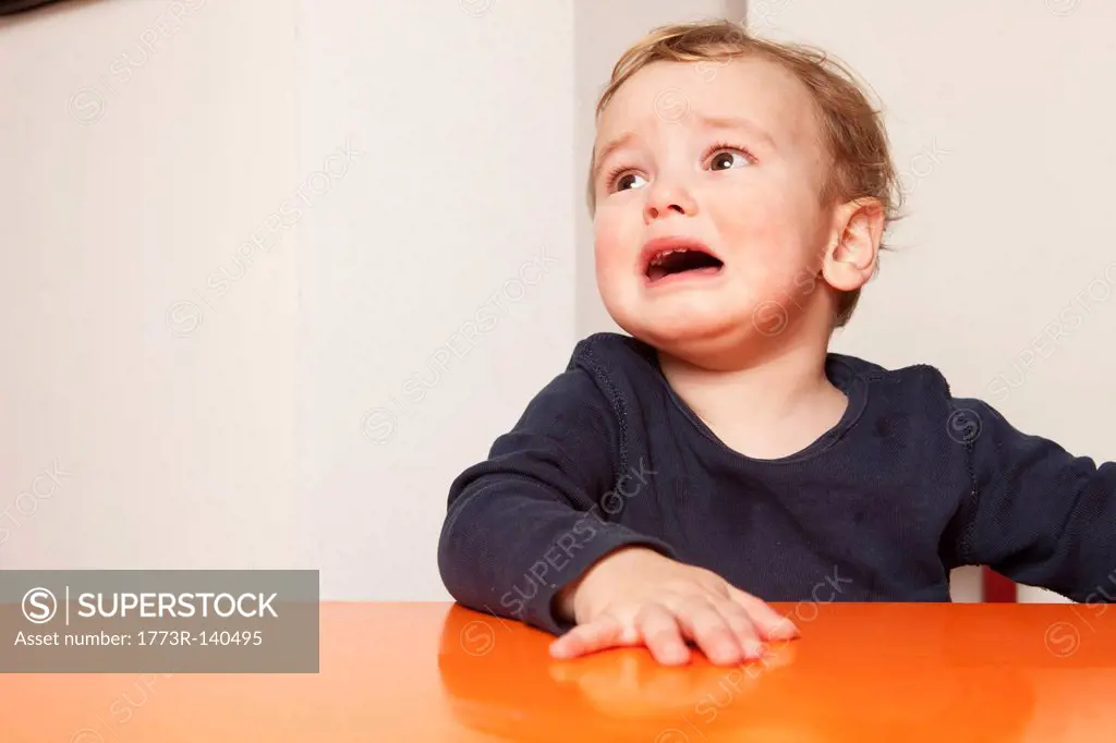 Little boy sitting on table crying