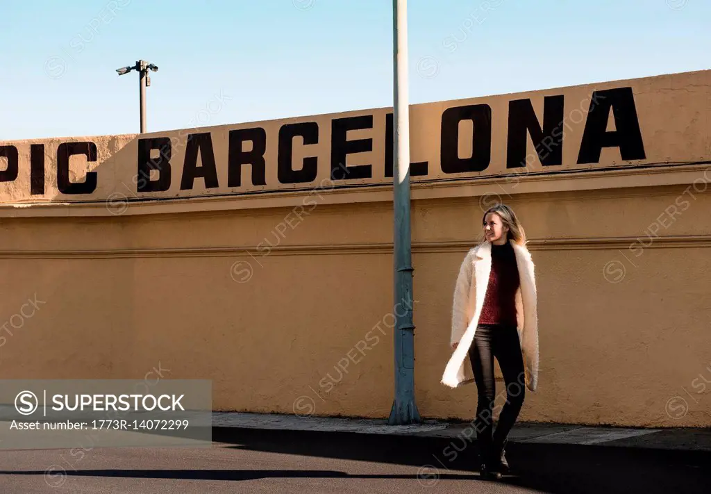 Female tourist strolling by wall with Barcelona in capital letters, Barcelona, Spain