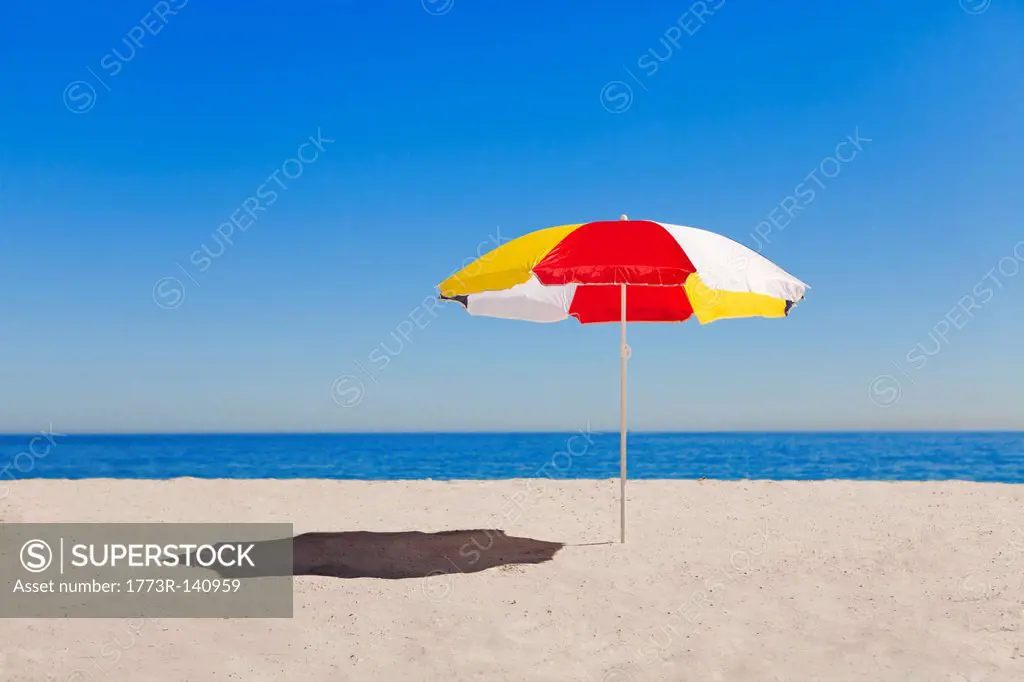 Umbrella in sand on empty beach