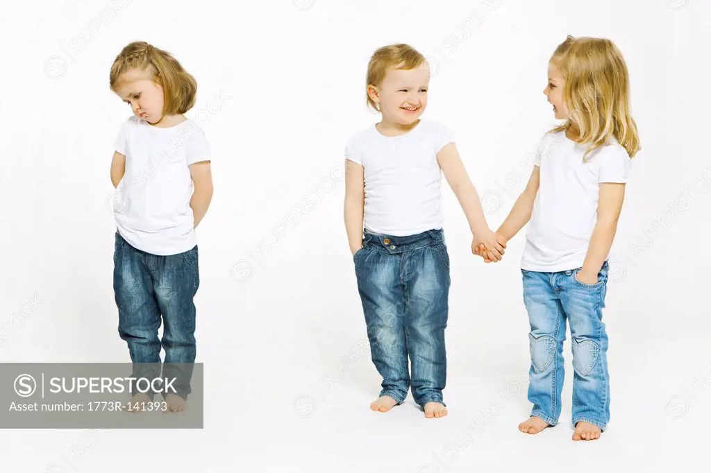 Two girls holding hands, third upset