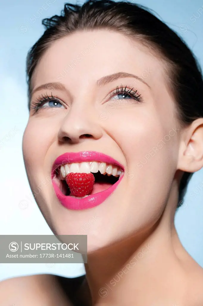 Smiling woman eating a raspberry