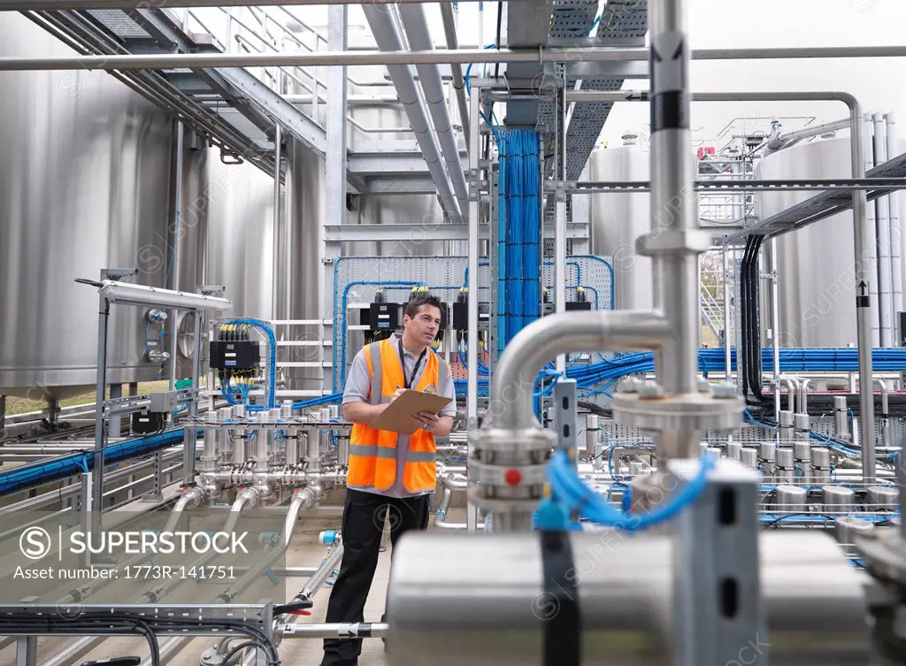 Worker with machinery in bottling plant