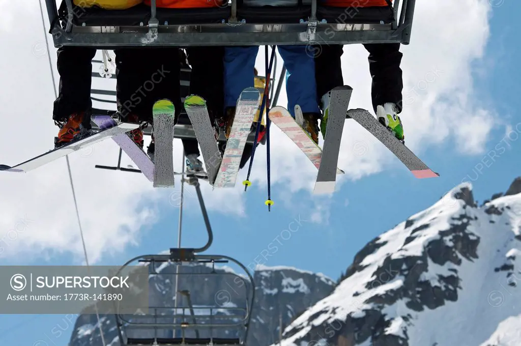 Skiers riding chair lift over mountains